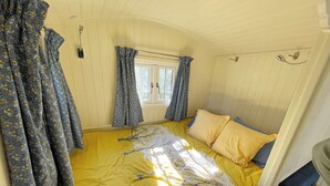 A room with a bed, curtains, a window, and a door. - The Shepherds Hut (Wallingford)