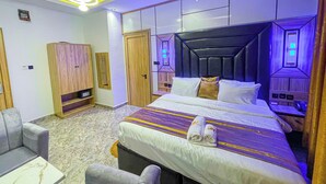 A modern hotel room with a bed, a sofa, a desk, and a wardrobe. - Julicis Hotels and Suites (Lagos)