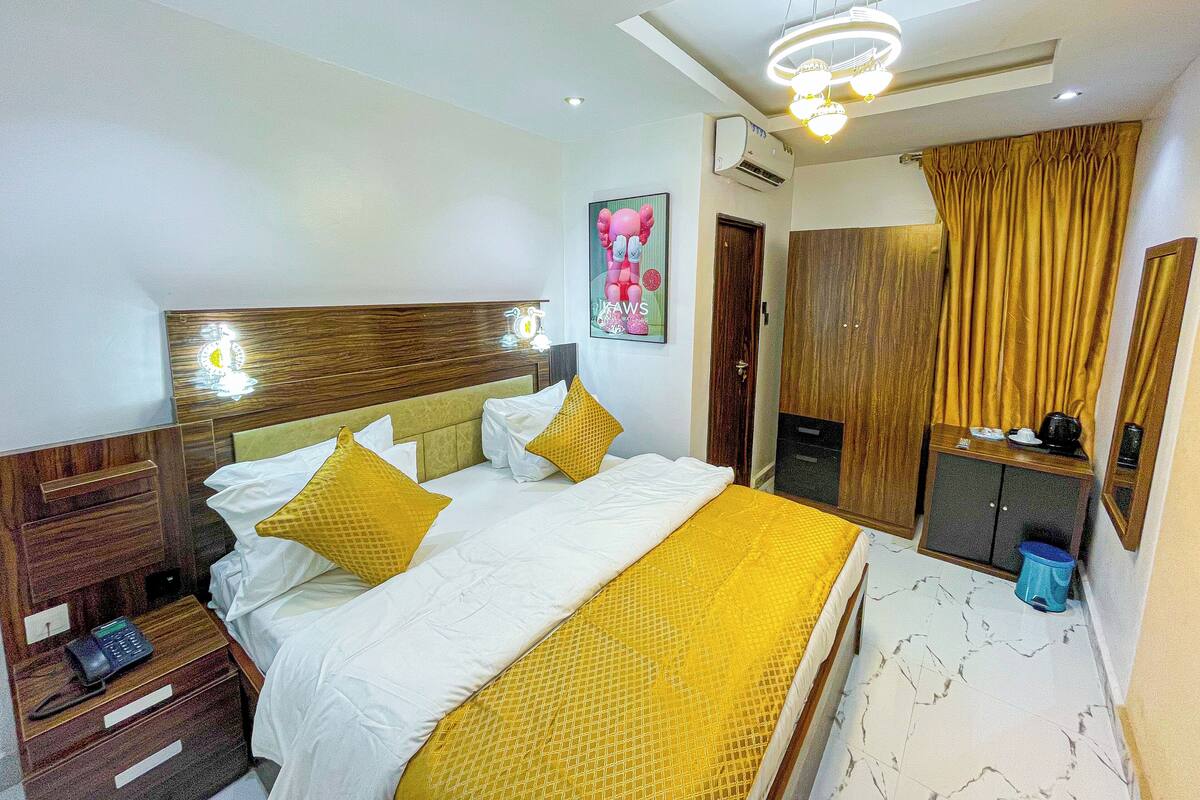 Una habitación de hotel con cama, mesita de noche y espejo.