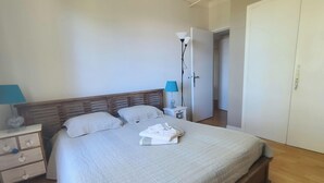 Un lit bien fait, avec des oreillers, une table de chevet avec une lampe et une armoire.