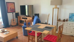 Un salon avec un téléviseur, une guitare, une table avec un set de table et un canapé.