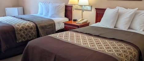 A hotel room with two beds, a nightstand with a lamp, and a framed picture on the wall.