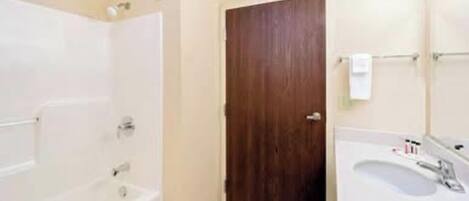 Un baño con bañera, ducha, lavabo y puerta de madera.