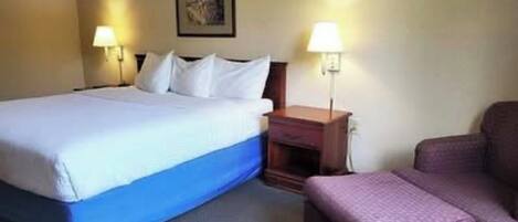 A hotel room with a bed, bedside tables, a chair, and a wall-mounted picture.