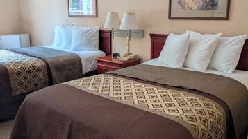 Une chambre d’hôtel avec deux lits, une table de chevet avec une lampe et deux tableaux encadrés au mur.