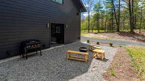 A modern building with a gravel patio, outdoor seating, and a grill.