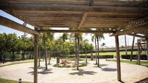 Un espacio al aire libre cubierto con un camino de ladrillo circular, palmeras y un parterre central.