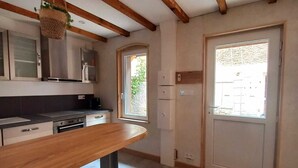 Una cocina con vigas de madera, un taburete de bar y una ventana.