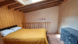 Una habitación con cama, cómoda y tragaluz.