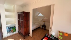 Un dormitorio con cama, armario, una mesita de noche con lámpara y un tablón de anuncios con notas.