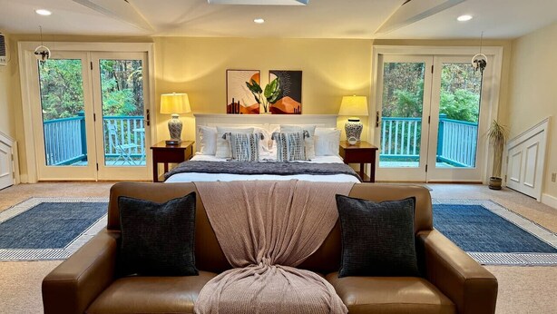 A bedroom with a large bed, two bedside tables, a window with a view, and a ceiling light. - Skylights & Tides King Studio - Kittery/Portsmouth (Eliot)