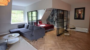 A modern living room with a sectional sofa, a round coffee table, and a glass partition. - Comfortable Apartment With a Private Sauna (gmina Stężyca)