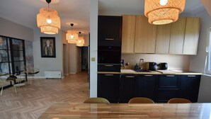 A modern kitchen with wooden cabinets, a dining area with a wooden table, and pendant lighting. - Comfortable Apartment With a Private Sauna (gmina Stężyca)
