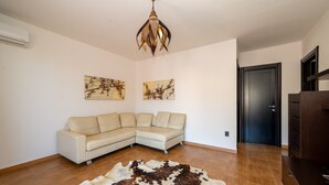 Ein Wohnzimmer mit einer Eckcouch, einem Kuhfellteppich und zwei Wandbildern.