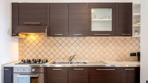 Eine moderne Küche mit dunklen Holzschränken, einer Edelstahlspüle und einem eingebauten Backofen.