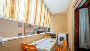 A balcony with a table and chairs, a washing machine, and a view of neighboring buildings. - Apartment 'Arancio' – Bright 2-Bedroom Retreat in La Maddalena (La Maddalena)