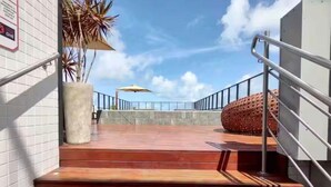 A staircase leading to a terrace with a metal railing, a concrete wall, and a large decorative rock. - Get One 607 · Flat Corais do Bessa with sea view for 4 people (João Pessoa)