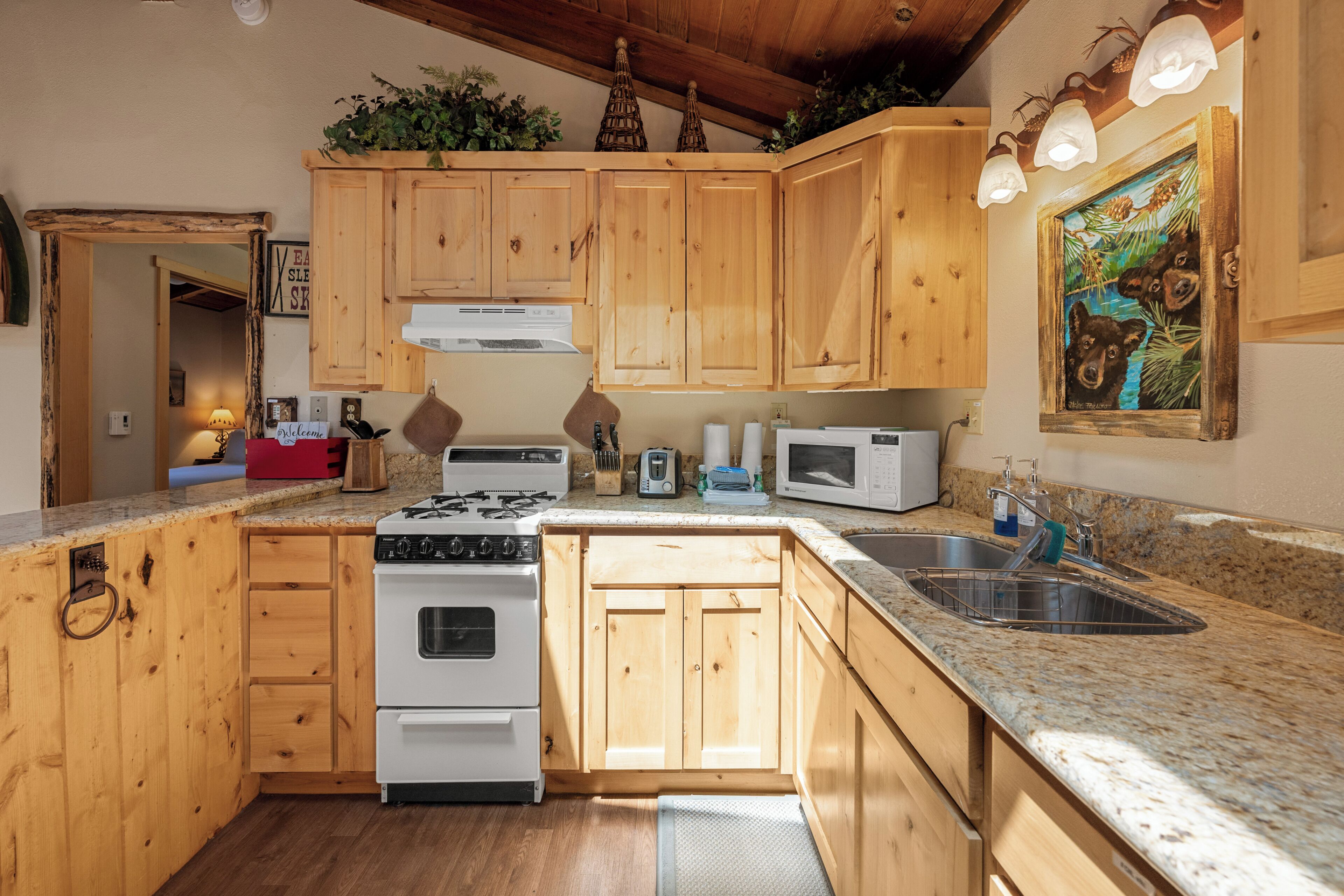 A kitchen with wooden cabinets, a gas stove, a microwave, and a sink.