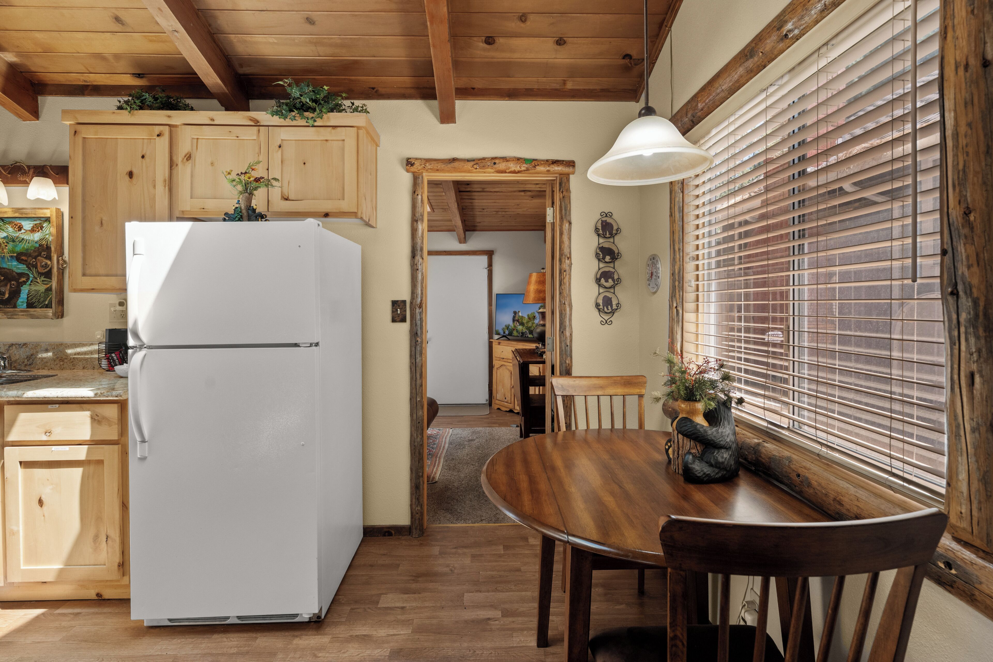 A kitchen with wooden cabinets, a white refrigerator, and a dining area with a wooden table and chairs.