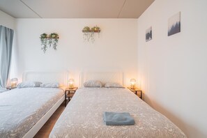 A double bed with a patterned bedspread, bedside lamps, and two wall-mounted plant holders. - Amazing Apartment in Antwerp (Antwerp)