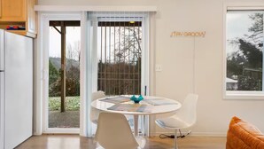 Eine moderne Küche mit Essbereich, einer Glasschiebetür, die zu einem Garten führt, und einem Schild an der Wand mit der Aufschrift 'STAY GROOVY'.