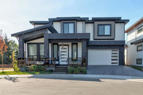 A modern two-story house with a garage, large windows, and a well-maintained front yard. - SERENE COASTAL ESCAPE (Surrey)