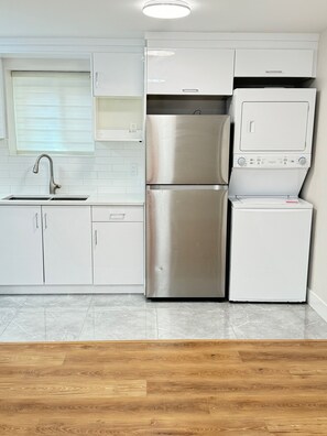 A modern kitchen with white cabinets, a stainless steel refrigerator, and a built-in oven. - SERENE COASTAL ESCAPE (Surrey)