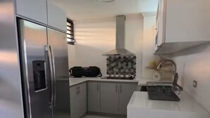 Et moderne køkken med rustfrie apparater, indbygget ovn og kaffemaskine.