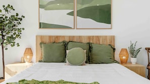 A bed with green bedding and pillows, a wooden headboard, bedside lamps, and a wall-mounted painting. - Dac1b - 90 Degrees by Experience Jervis Bay (Vincentia)