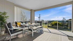 Un balcón con mesa y sillas, una planta en maceta y vistas a la ciudad.