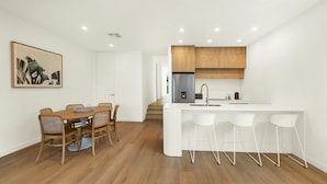 A modern kitchen with wooden cabinets, a white countertop, and a stainless steel refrigerator. - Vinny Ocean View by Experience Jervis Bay (Vincentia)