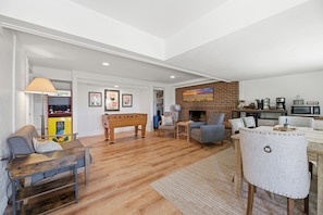 A spacious living room with a foosball table, a sofa, a coffee table, and a fireplace.
