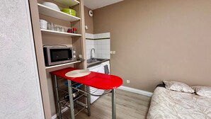 A compact kitchenette with a microwave, sink, and storage shelves.