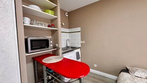A compact kitchenette with a microwave, sink, and storage shelves.