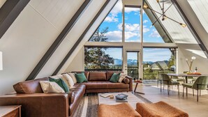 Loft moderno con un'ampia finestra a lucernario, un divano in pelle marrone e zona pranzo con sedie.