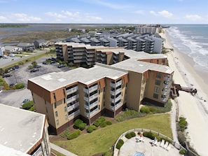 Ein Apartmentkomplex direkt am Strand mit mehreren Gebäuden, einem Parkplatz und Blick auf den Strand.