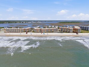 Ein Hotel direkt am Strand mit mehreren Gebäuden, einem Sandstrand und Blick auf den Ozean.
