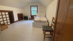 Een kamer met een bed, een stoel, een kaptafel, een raam en een plafondlamp.
