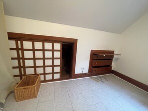 Ein Zimmer mit einer Schiebetür, einem Holzschrank und einem Korbwäschesammler.