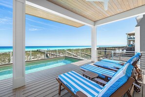 Un espace aménagé au bord de la piscine, avec des chaises longues et une vue sur l’océan.