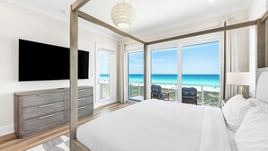 A bedroom with a large bed, a TV, a dresser, and a balcony with a view of the ocean. - 💎 Share My Lowecation! Brand New Lux 6BR Beachfront! Pool, Pets, Sleeps 16 (Navarre Beach)
