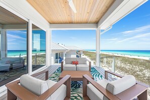 Una habitación moderna frente a la playa, con techo de madera, ventanas amplias y vistas al mar.