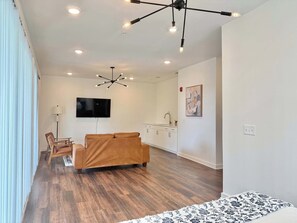 A modern living room with a sofa, a TV, and a dining area with a table and chairs. - 10 Guest Penthouse Multi-Level Condo in ATL! (Atlanta)