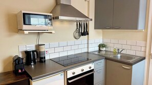 Eine kleine Küche mit Mikrowelle, Herd, Spüle und einem kleinen Topfpflanzen.