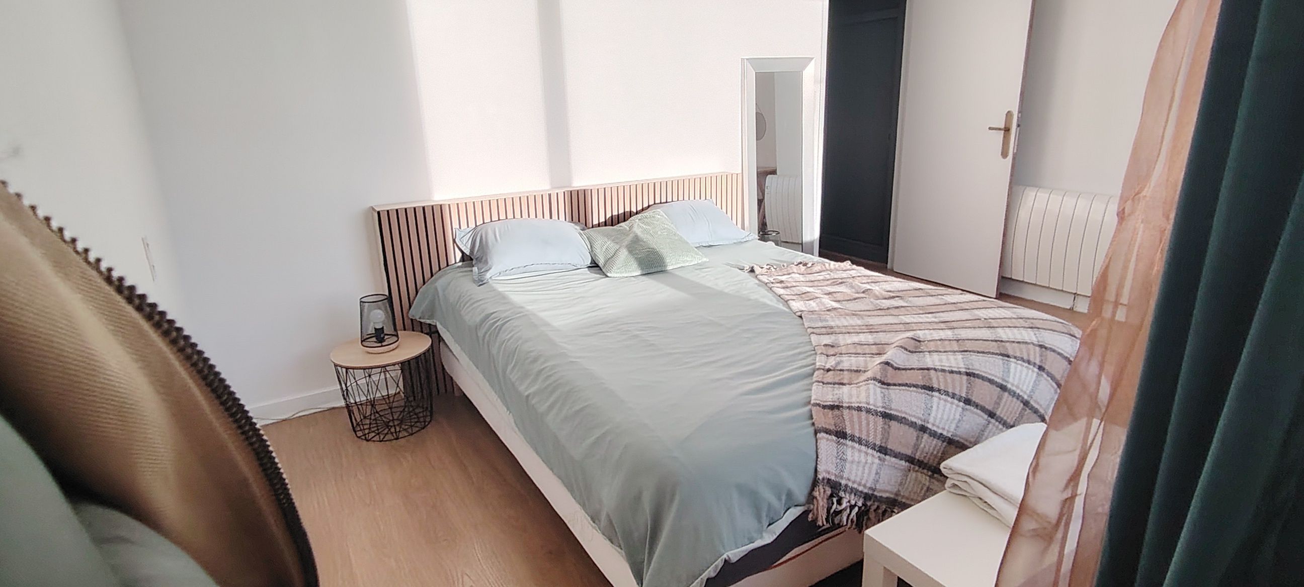 Ein Schlafzimmer mit Bett, Nachttisch und Spiegel.
