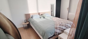 A bedroom with a bed, bedside table, and a mirror.