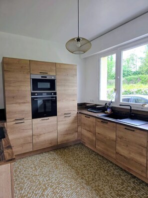 A modern kitchen with wooden cabinets, a built-in oven, and a window providing a view of the outdoors.
