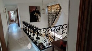 A hallway with a staircase, a patterned wall hanging, and a decorative curtain. - Normandy: Chic & Authentic (Beaumont-le-Roger)