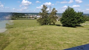 A grassy field with trees and a distant view of a town. - Normandy: Chic & Authentic (Beaumont-le-Roger)