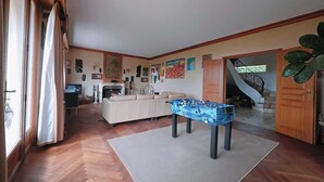 A spacious living area with a sofa, a foosball table, and a fireplace. - Normandy: Chic & Authentic (Beaumont-le-Roger)